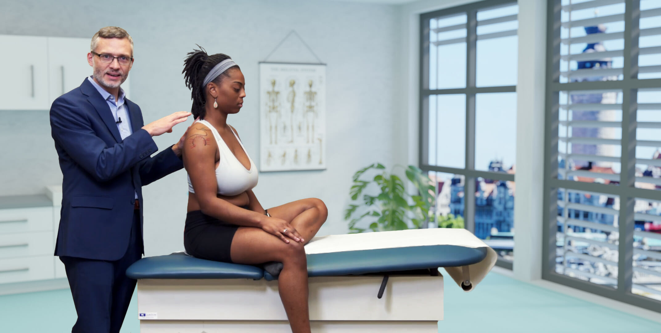 Healthcare professional examining a woman's shoulder in a lecture hall.
